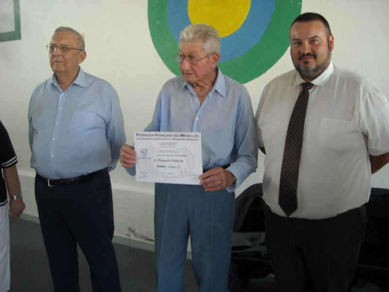 Monsieur Narcisse BECHEMIN présente le Diplôme accompagnant la Plaquette . Il est entouré du Président fédéral et du représentant de l'Etat,...